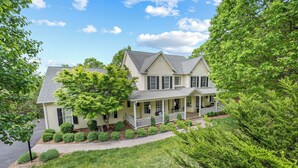 A two-story house with a porch, surrounded by well-maintained lawns and trees. - Evergreen Estate (Blacksburg)