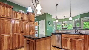 A kitchen with wooden cabinets, a central island, stainless steel appliances, and pendant lighting. - Evergreen Estate (Blacksburg)