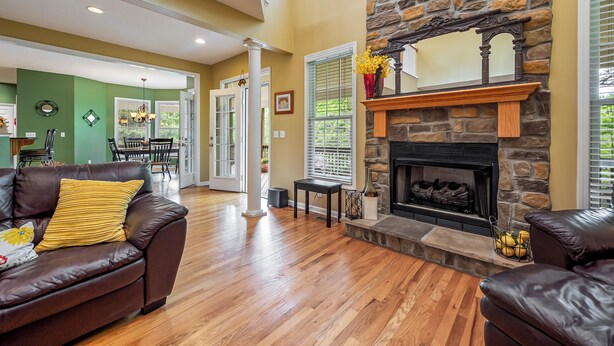 A spacious living room with a stone fireplace, leather sofas, and hardwood flooring. - Evergreen Estate (Blacksburg)