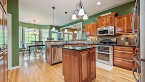 A spacious kitchen with wooden cabinets, stainless steel appliances, and a large island. - Evergreen Estate (Blacksburg)
