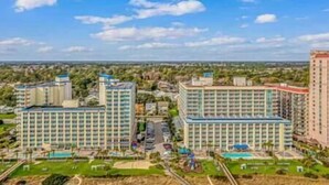A high-rise hotel with multiple floors, a swimming pool, and a landscaped area with trees. - 2BR Penthouse End Unit w/ Indoor Waterparks! (Myrtle Beach)