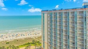 A high-rise hotel with multiple balconies overlooking a beach. - 2BR Penthouse End Unit w/ Indoor Waterparks! (Myrtle Beach)