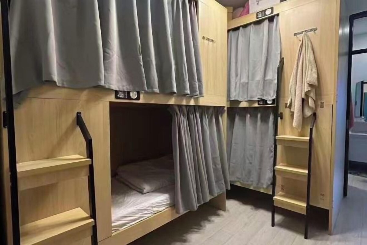 A bunk bed room with curtains, a shelf, and a towel rack.