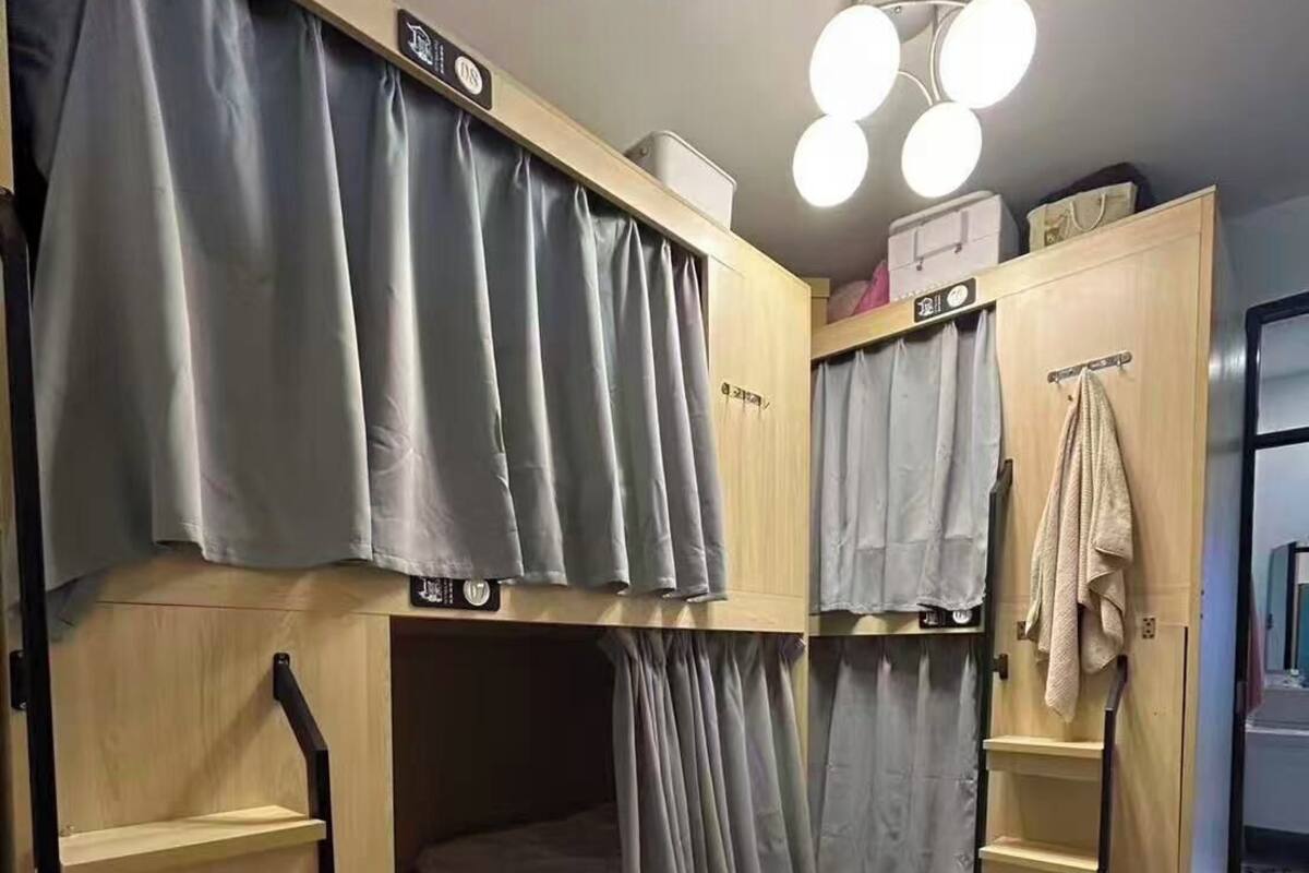 Un dormitorio con literas, un estante, un perchero y una lámpara en el techo.