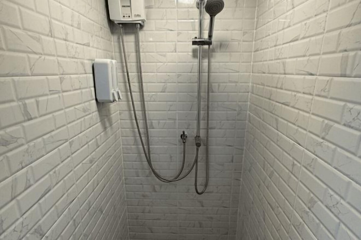 Een douche met een handdouche en een wandmengkraan, verbonden door een flexibele slang.