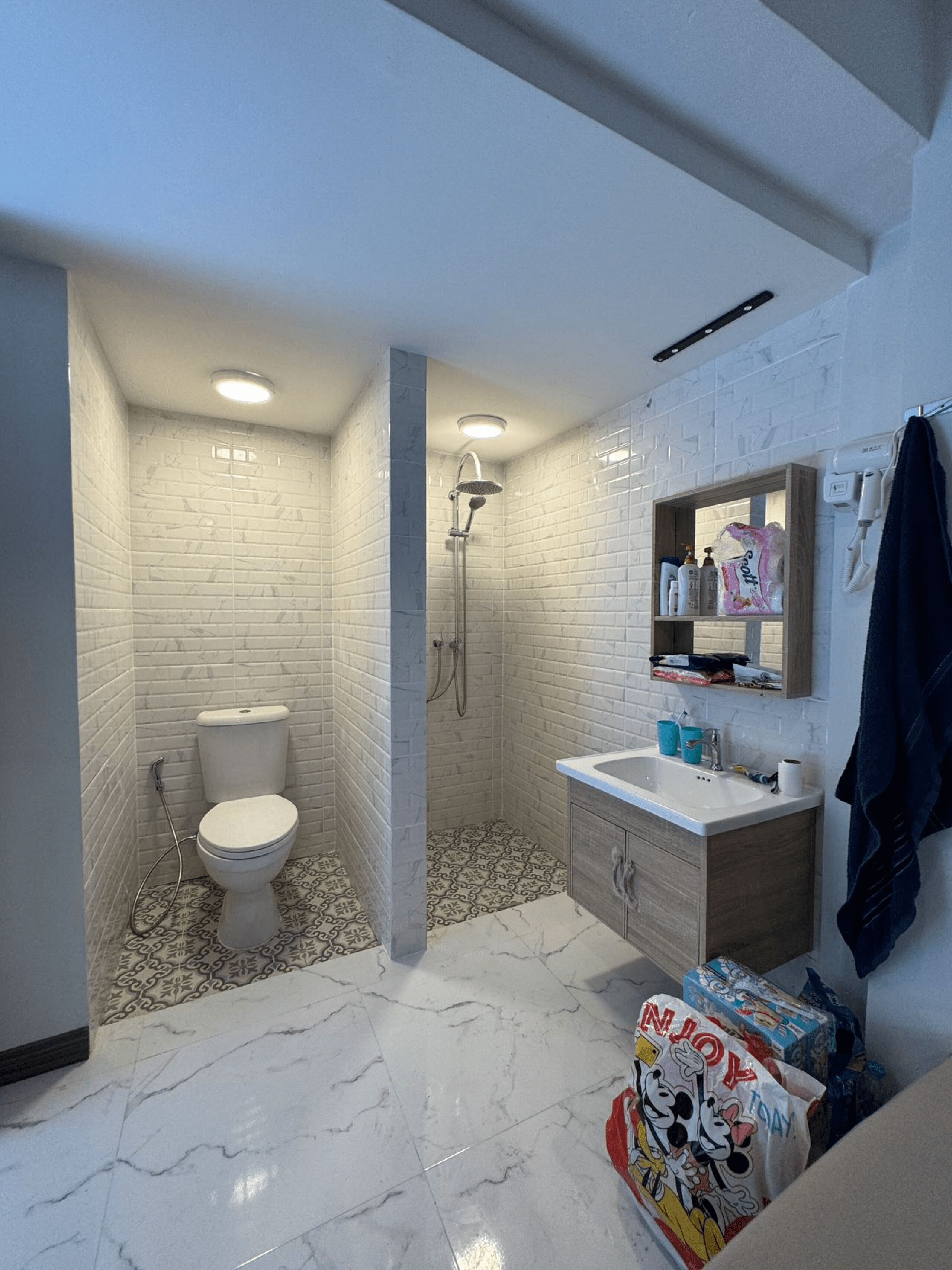 Un baño con inodoro, ducha, tocador y espejo.