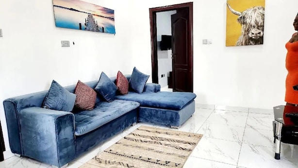 Una sala de estar moderna con un sofá modular azul, una alfombra estampada y obras de arte en las paredes.