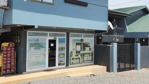 Un edificio con fachada azul, entrada protegida por una reja y un cartel anunciando servicios de ingeniería.