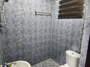Une salle de bain avec des murs en marbre, des toilettes et une baignoire.