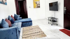 Una sala de estar moderna con un sofá azul, un televisor de pantalla plana y una mesa de centro de madera.