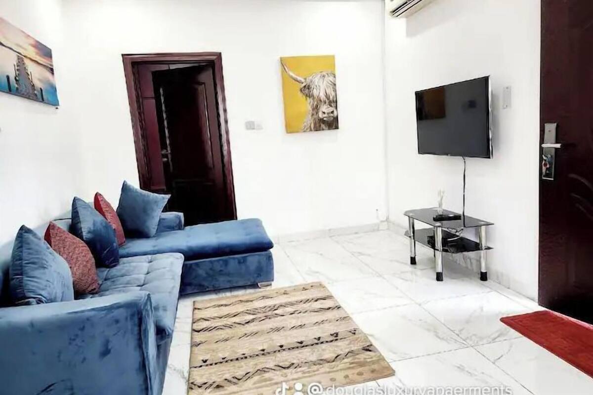 Uma sala de estar moderna com um sofá azul, uma TV de tela plana e uma mesa de centro de madeira.