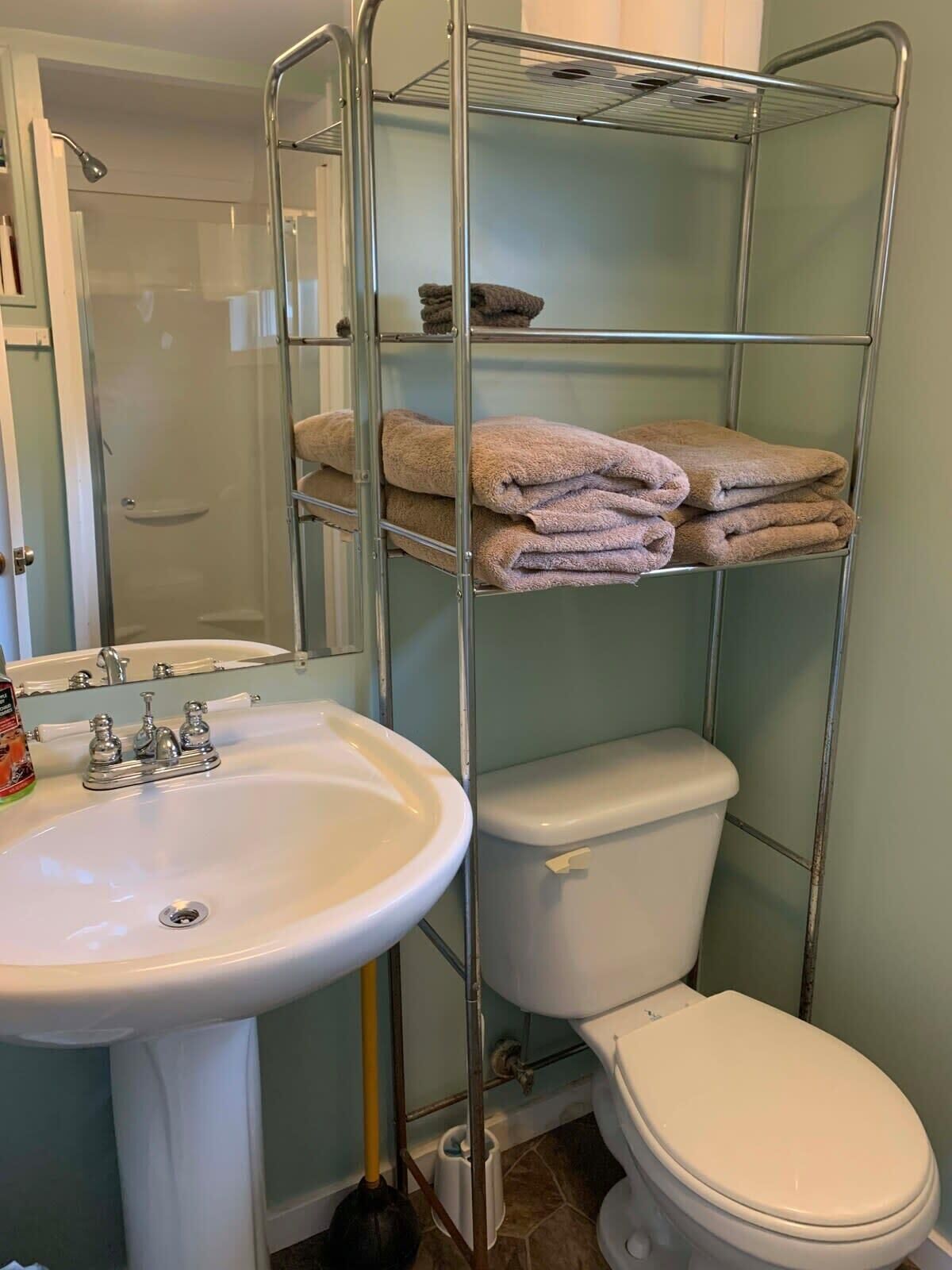 A bathroom with a white sink, toilet, and a metal towel rack with folded towels.