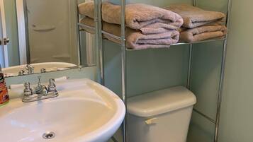 A bathroom with a white sink, toilet, and a metal towel rack with folded towels.