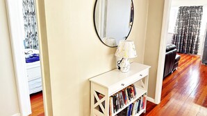 A room with a white console table, a mirror, and a bookshelf filled with books.