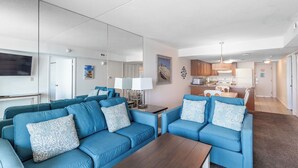 A modern living room with blue sofas and a wooden coffee table. - 2BR Near Beach | Bay Views + Jolly Roger Fun (Ocean City)