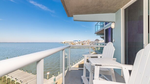 A balcony with a view of the sea and a pier in the distance. - Salty Air & Sunset Chairs | Bayfront Bliss in OCMD (Ocean City)
