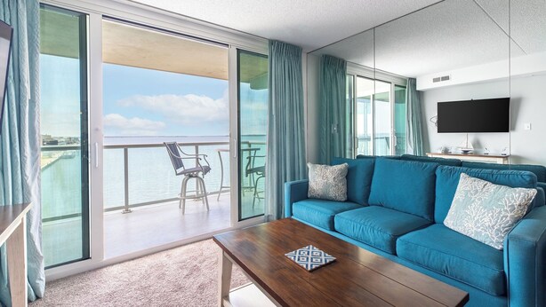 A modern living room with a blue sofa, a wooden coffee table, and a large TV on the wall. - Fries, Ferris Wheels & Bay Views | Your OCMD Getaway (Ocean City)