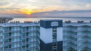 A multi-story hotel with a rooftop pool area and a view of the ocean at sunset. - Fries, Ferris Wheels & Bay Views | Your OCMD Getaway (Ocean City)