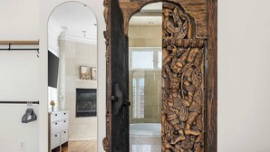 A bedroom with a wooden door, a bed, and a hallway leading to a bathroom. - Luxury Rooftop Penthouse - King Street! (Charleston)