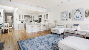 A spacious living area with a large coffee table, a sofa, and a dining area with chairs. - Luxury Rooftop Penthouse - King Street! (Charleston)