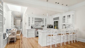 A spacious kitchen with white cabinetry, a marble countertop island, and wooden flooring. - Luxury Rooftop Penthouse - King Street! (Charleston)