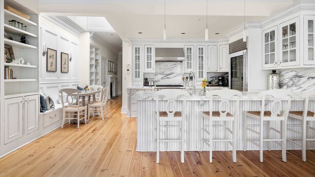 A spacious kitchen with white cabinetry, a marble countertop, and a central island with bar stools. - Luxury Rooftop Penthouse - King Street! (Charleston)