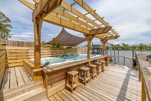 A wooden deck with a hot tub and bar stools, overlooking a body of water. - Driftwood, jet ski pad, boat dock! (Panama City)