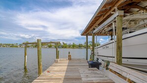 A wooden dock extending into calm water, with a boat docked on the right and a covered area on the left.