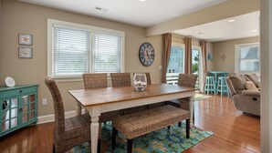 A dining area with a wooden table, wicker chairs, and a clock on the wall.
