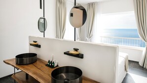 Een moderne badkamer met een houten wastafelmeubel, twee zwarte wasbakken en een grote spiegel.