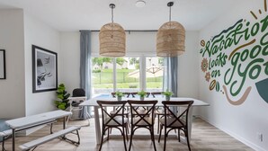 A dining area with a table and chairs, a bench, and a wall with a motivational quote.