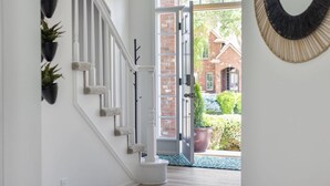 A staircase with a white railing, potted plants, and a door leading to a brick exterior.
