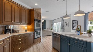 A modern kitchen with wooden cabinets, stainless steel appliances, and pendant lighting.