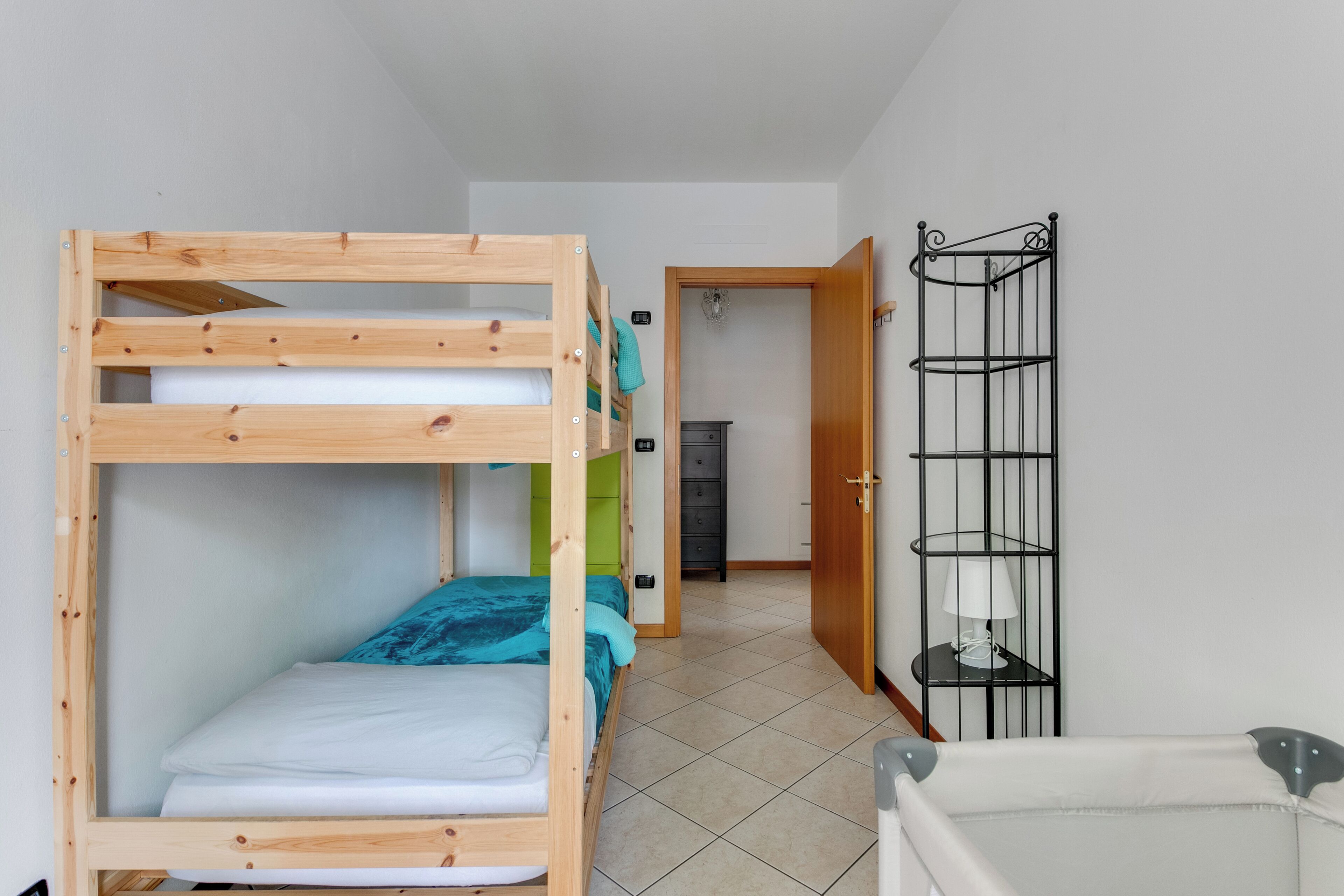 A bunk bed room with a wooden frame, a small desk, and a metal shelf unit.