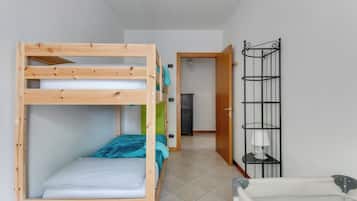 A bunk bed room with a wooden frame, a small desk, and a metal shelf unit.