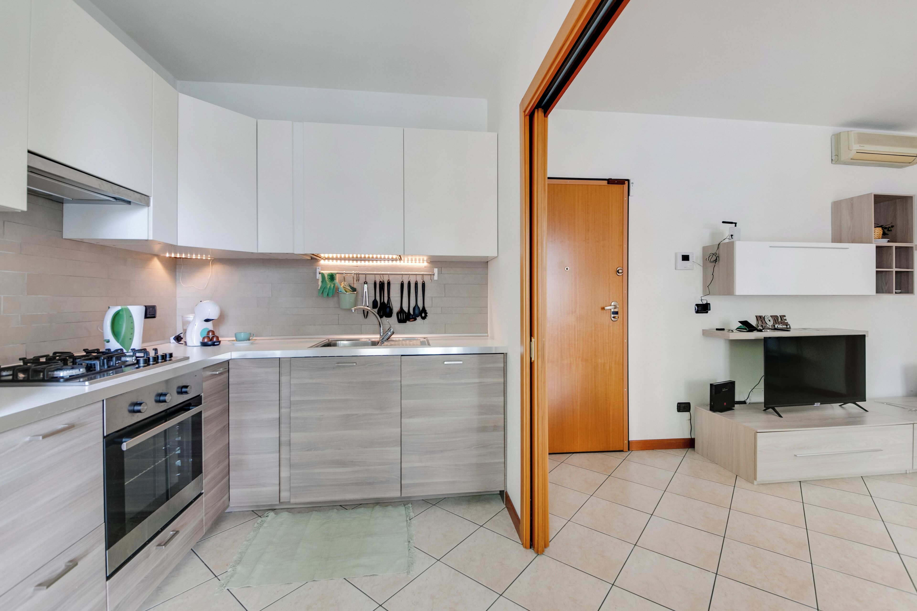 A modern kitchen with a built-in oven, a sink, and a countertop with a kettle.