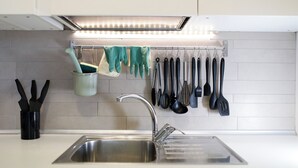 A kitchen with a stainless steel sink, hanging utensils, and a pot rack. - 2 Bedroom Apartment in Cesena (Cesena)