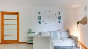 A modern living room with a white sofa, a glass coffee table, and a wall clock. - 2 Bedroom Apartment in Cesena (Cesena)