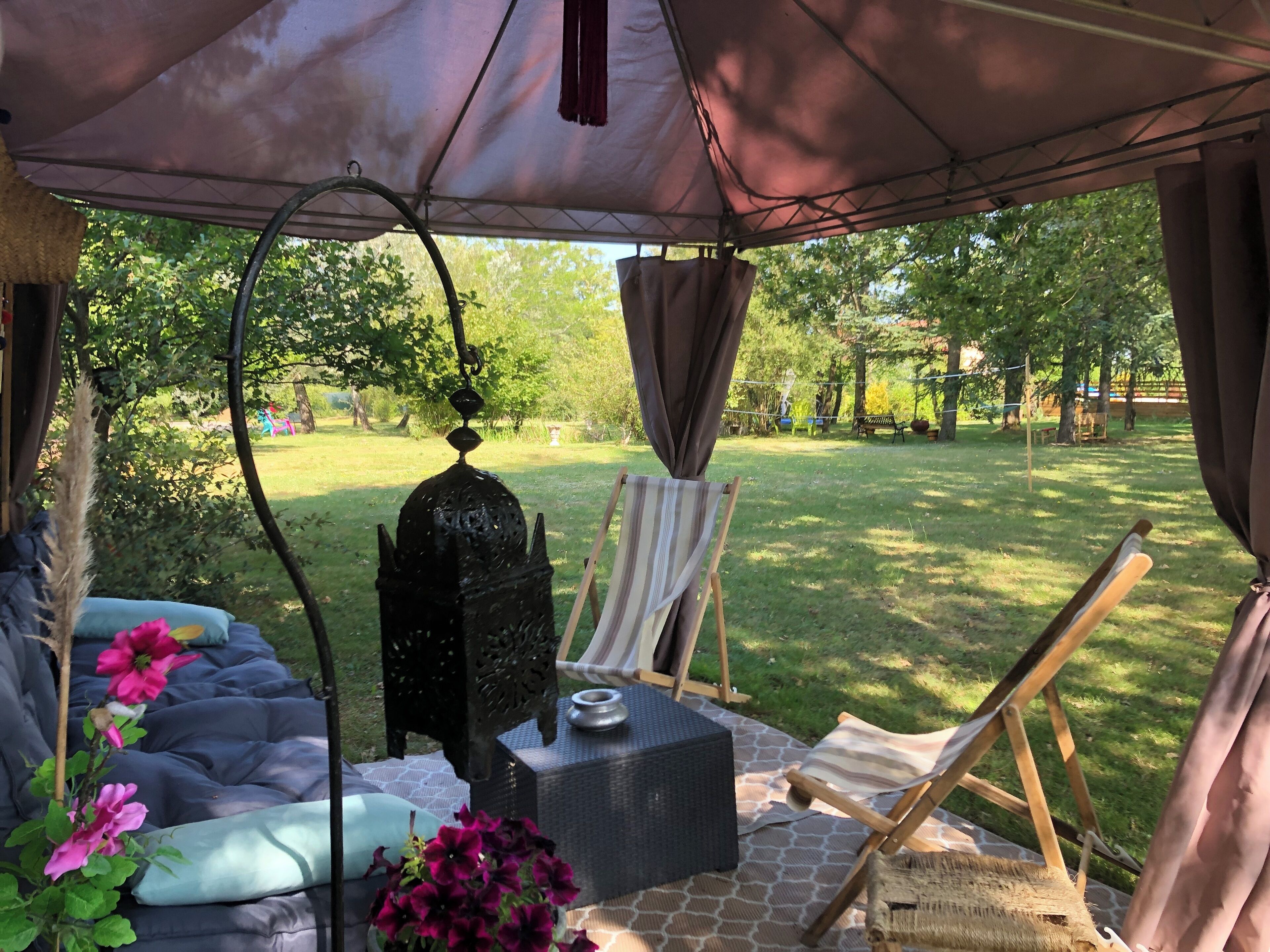 Un área de estar al aire libre techada, con un sofá, una silla y una mesa.