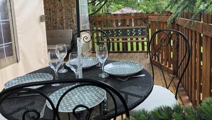 An outdoor dining area with a table set for four, surrounded by a wooden fence and greenery.