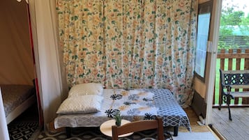A cozy room with a bed, a small table with a plant, and a bench outside.