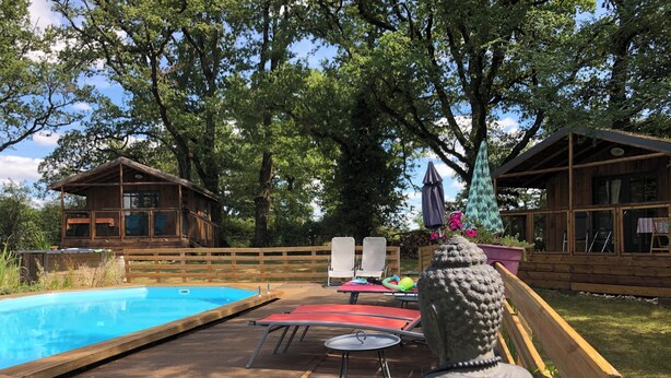 A wooden deck with a swimming pool, lounge chairs, and a statue.