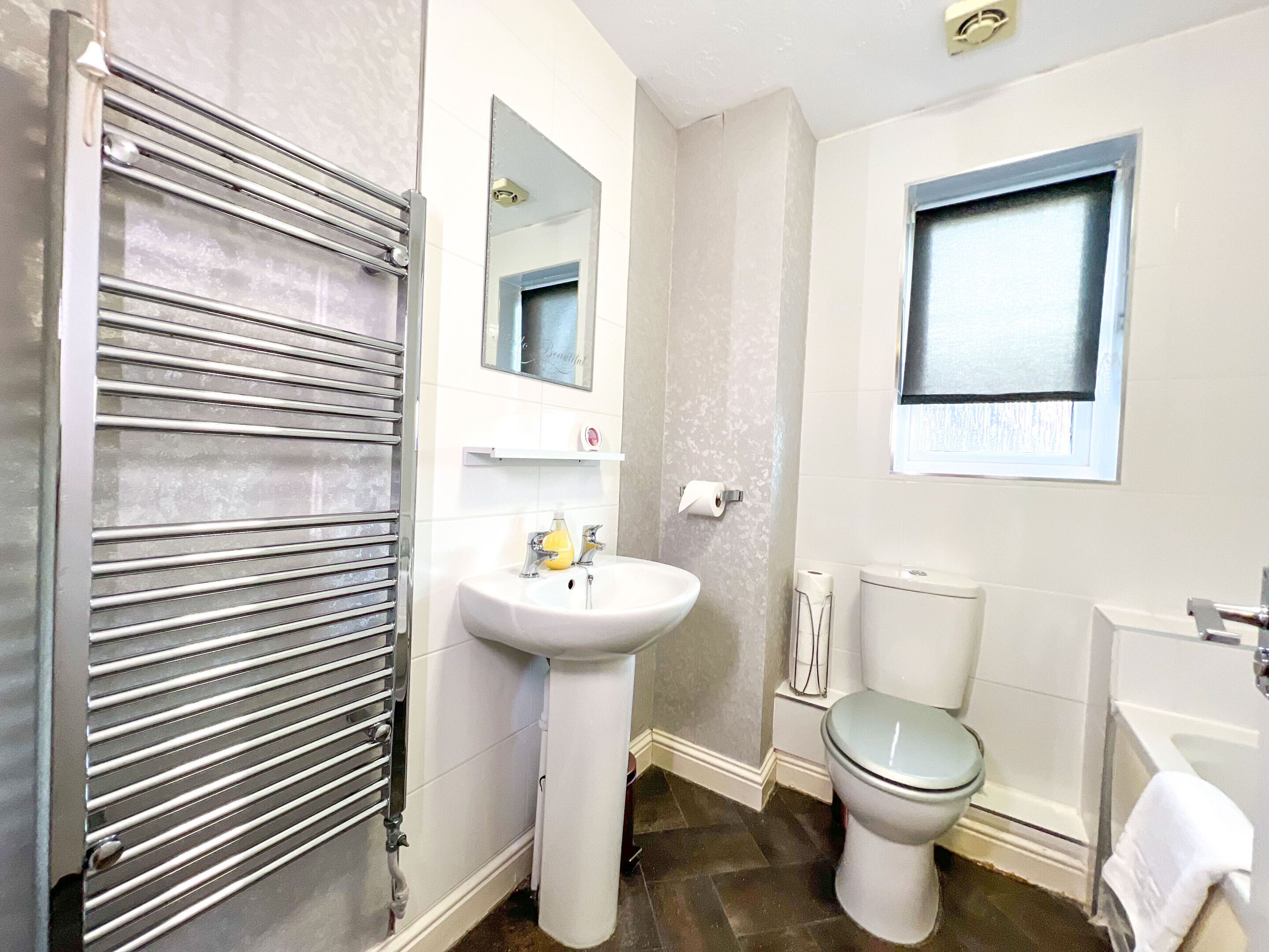 A bathroom with a toilet, sink, and a towel rack.