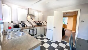 Una cocina compacta con piso a cuadros, microondas, pileta y refrigerador.