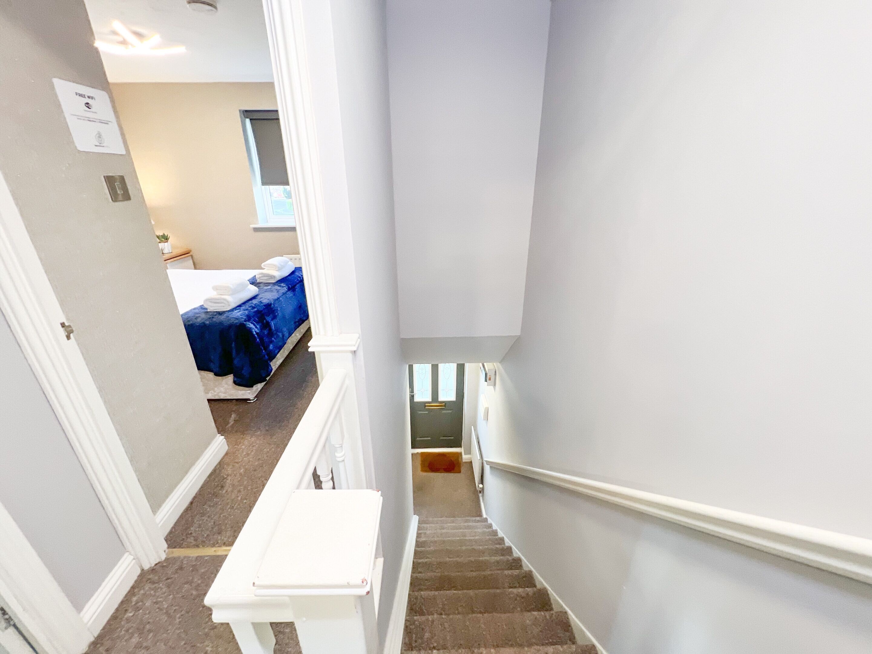 A staircase leading to a bedroom with a bed covered in blue bedding and white towels.