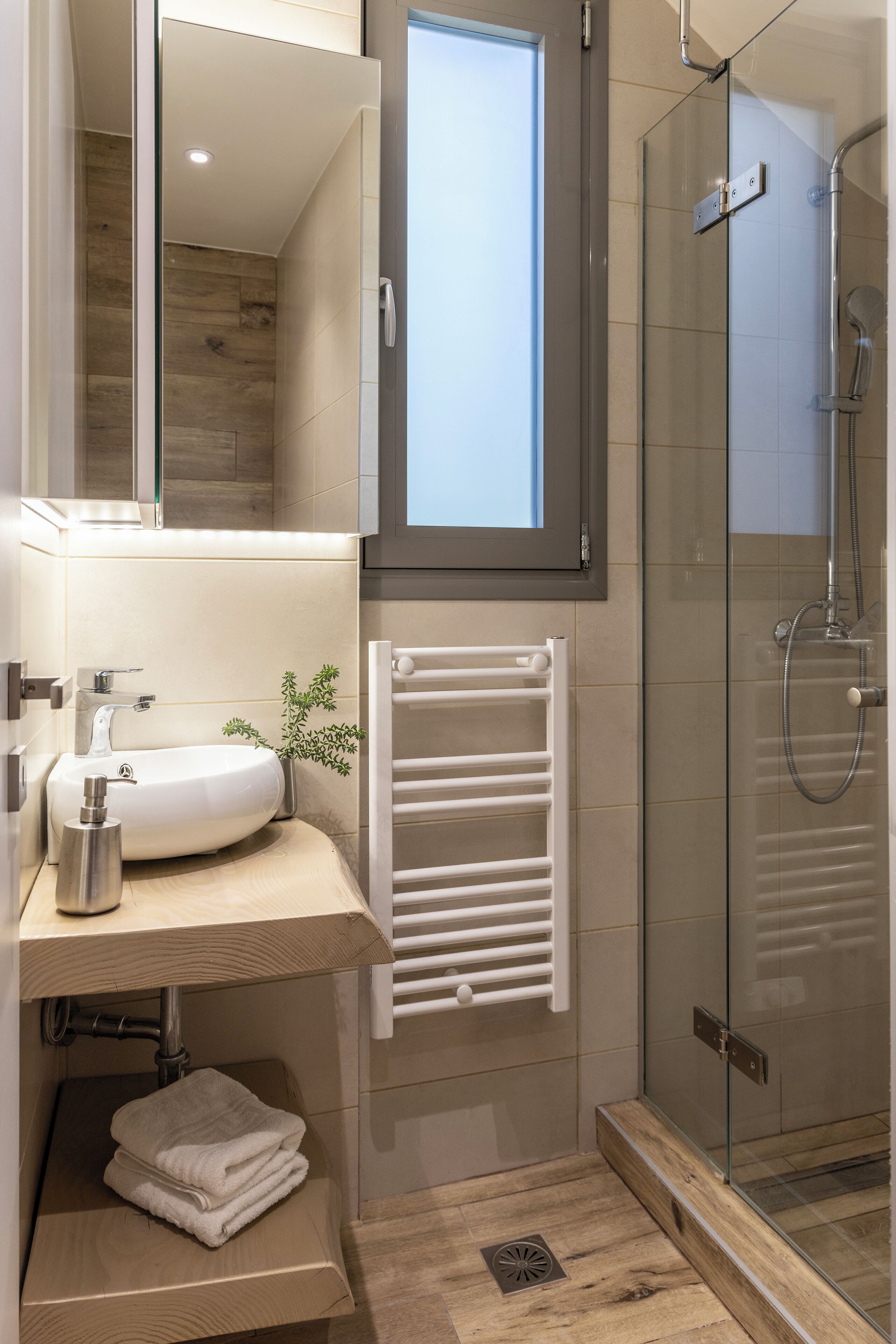 Un baño moderno con ducha de vidrio, lavamanos blanco y barra para toallas.