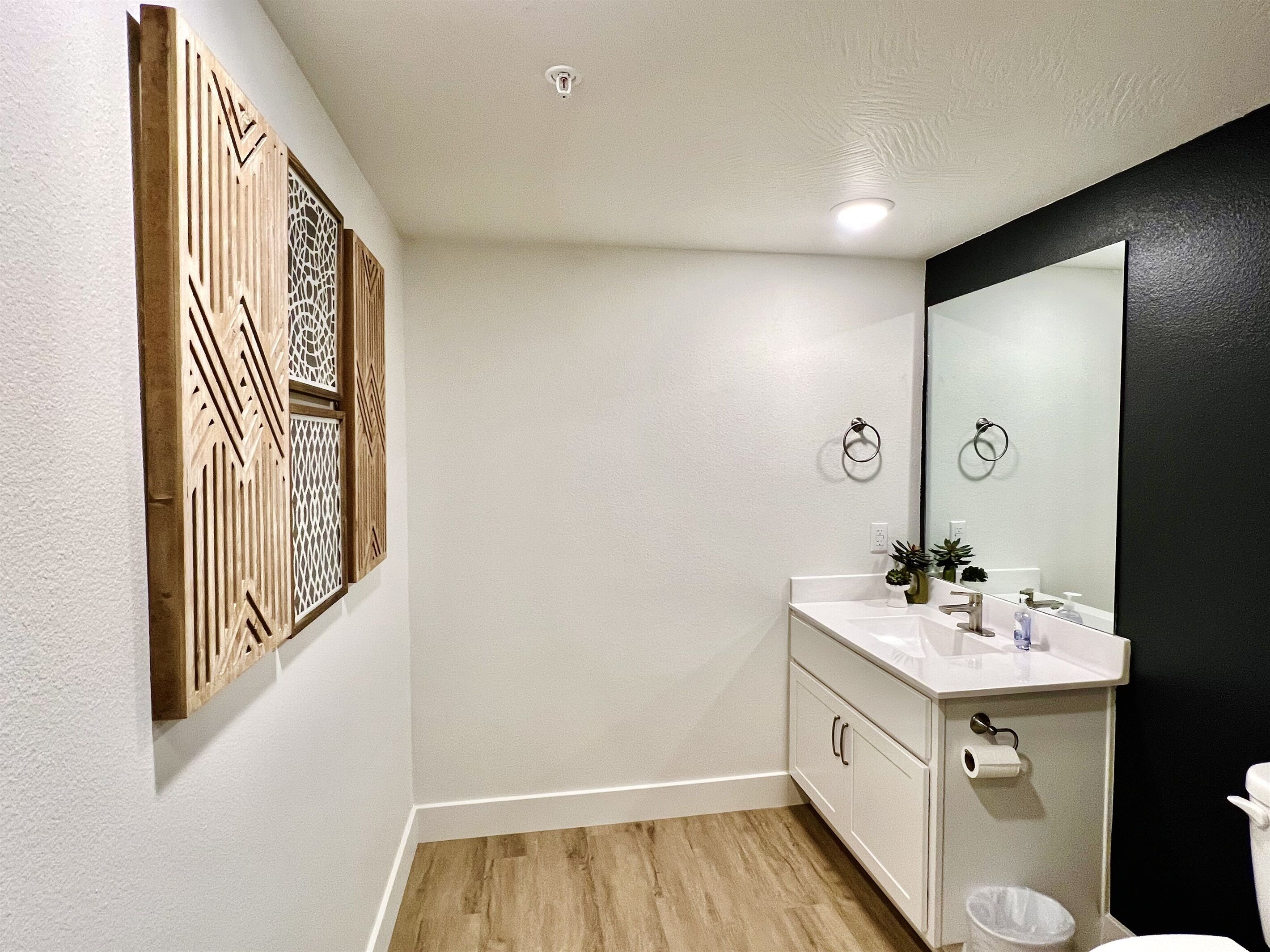 A bathroom with a wooden decorative panel, a white sink, a mirror, and a toilet.