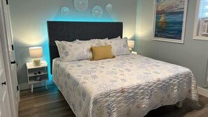 Ein Schlafzimmer mit einem Bett, Nachttischen, einer Wanduhr und einem Gemälde.