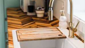 Een keuken met een witte spoelbak, een houten aanrechtblad en een moderne kraan.