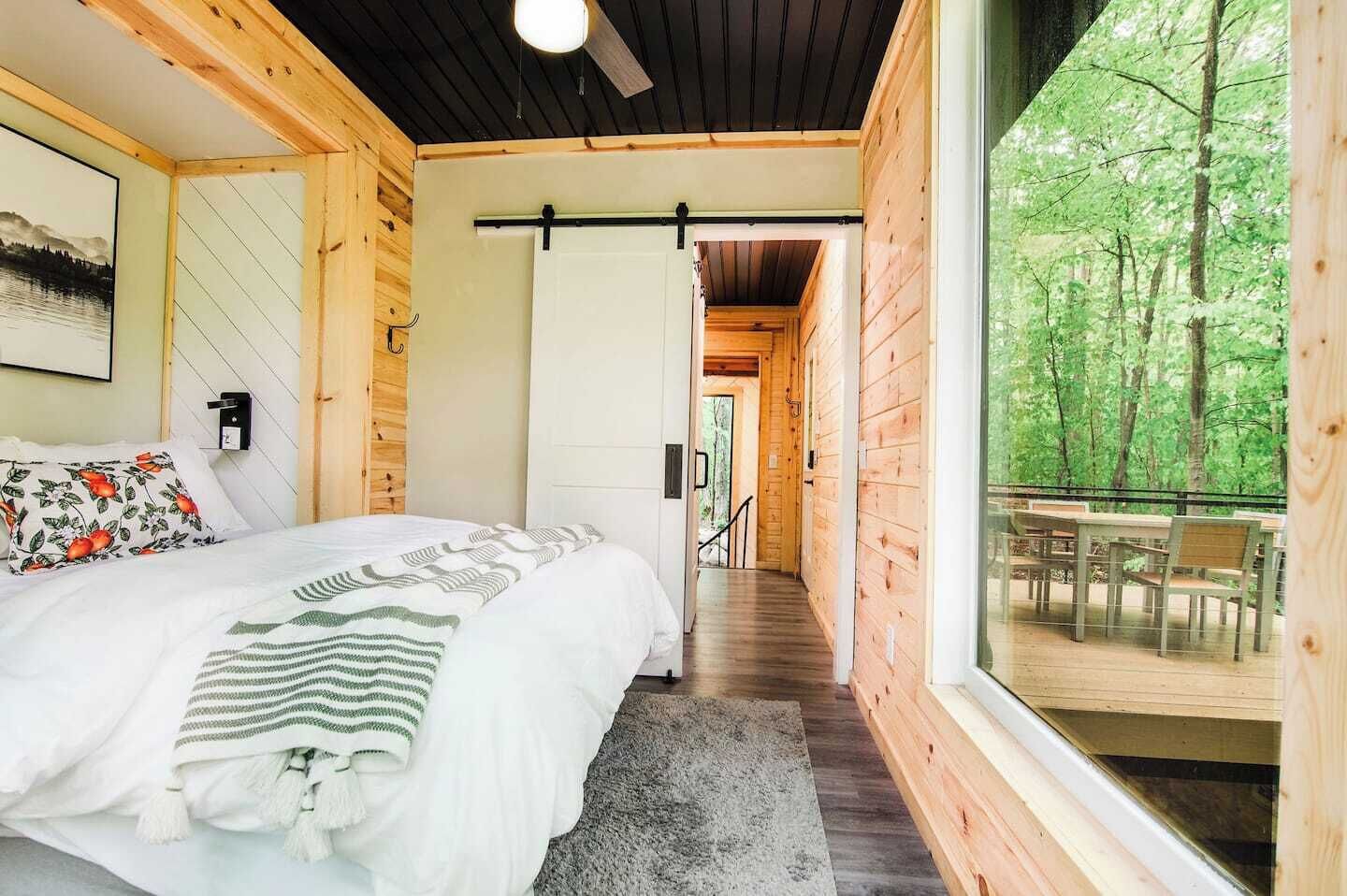 Une chambre dans une cabane en bois, avec un lit, une fenêtre et une vue sur la forêt.